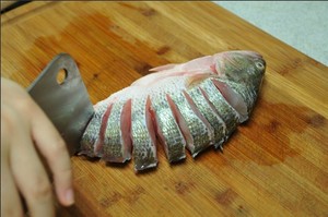 將鱸魚(yú)清洗干凈，從脊椎處切斷至腹部，腹部保留1cm左右不要切斷。
