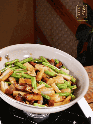 油熱下蒜末、干辣椒、醬肉煸炒出香味，依次下藕條、豆角翻炒均勻
